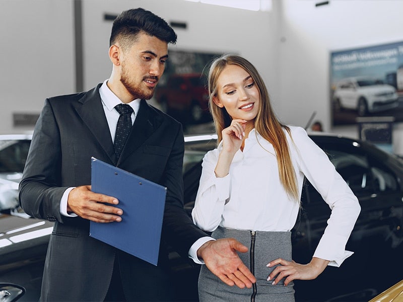 Salesman showcasing cars in a showroom.