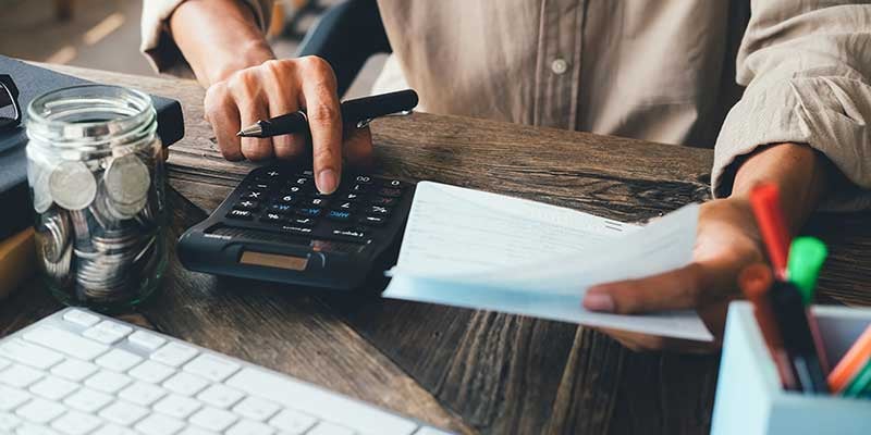 Man using a calculator with coins and papers on the table.