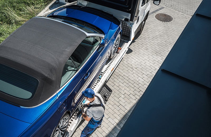 Technician loading a car onto a truck for transport.