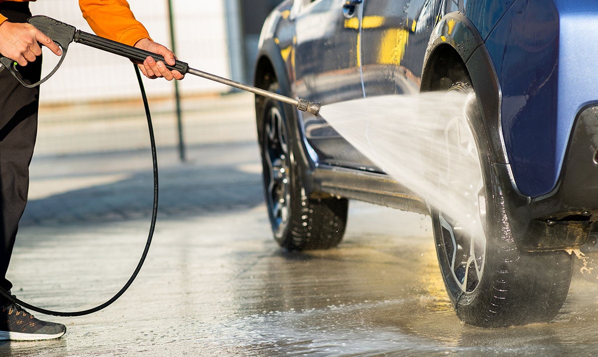 Man washing car with high-pressure jet spray