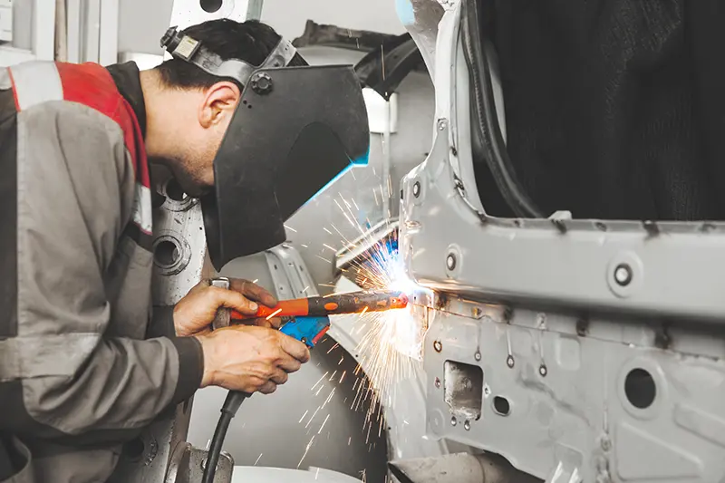 Technician welding a car during repair