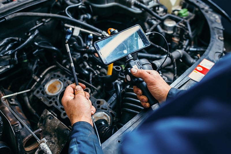 Technician inspecting an engine with diagnostic tools